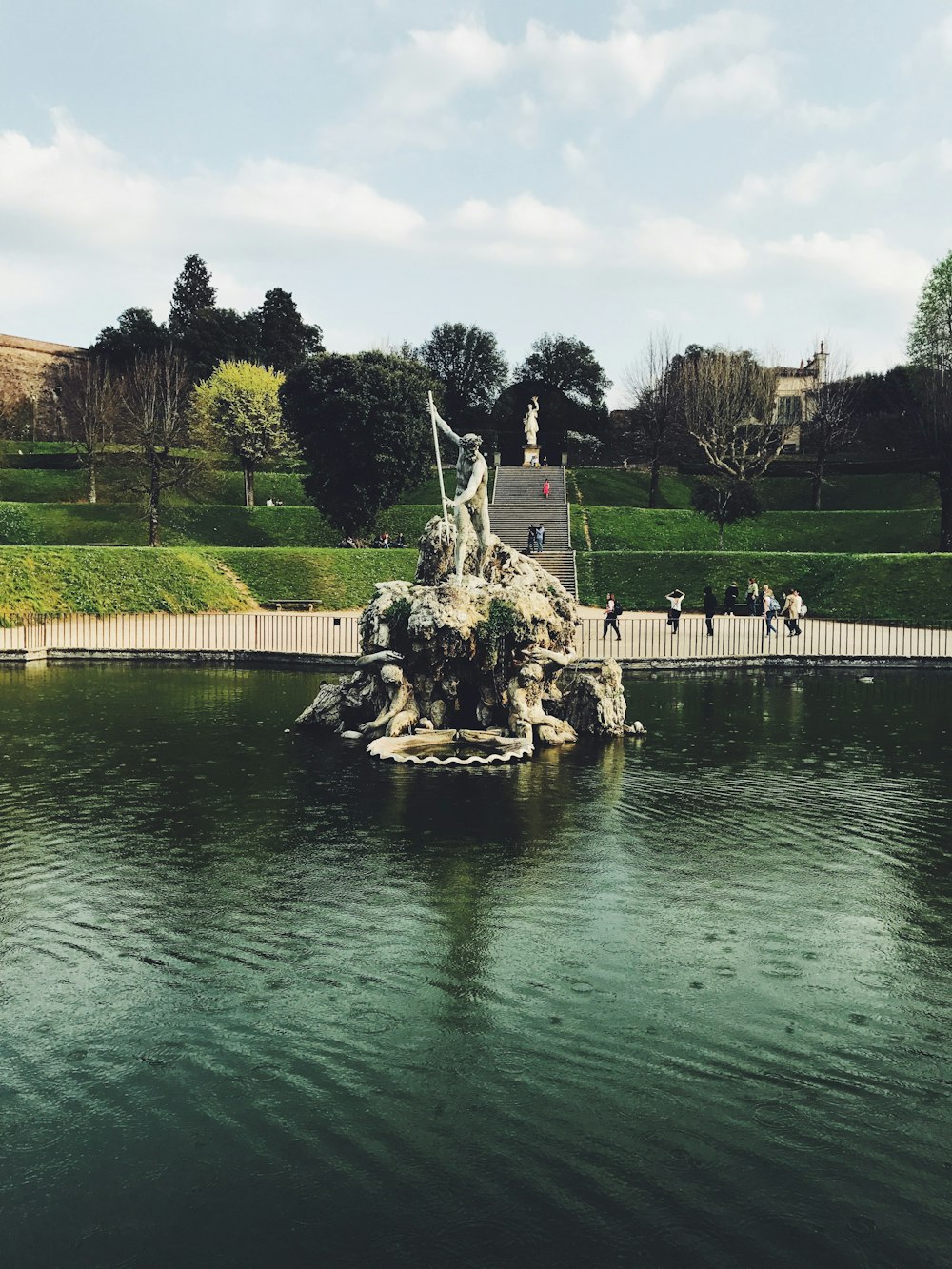 brown concrete fountain near green grass field during daytime