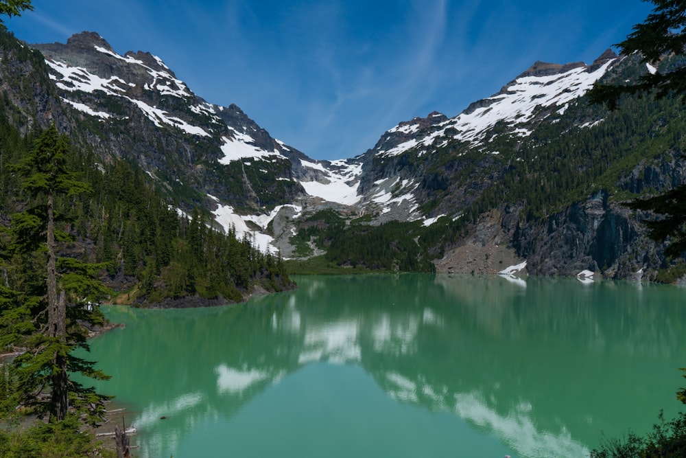 lake in the middle of the forest and snow covered mountains