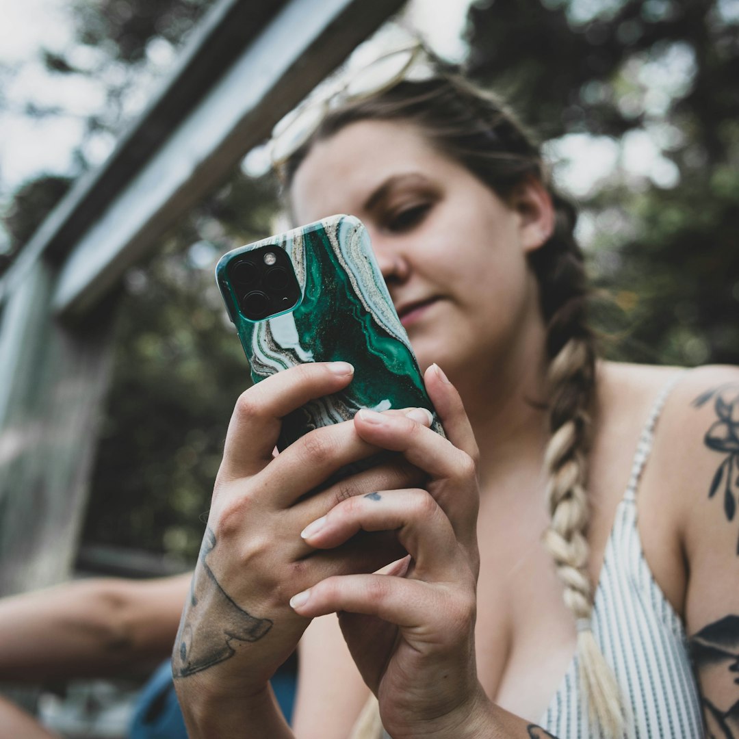 woman in white and blue stripe shirt holding iphone