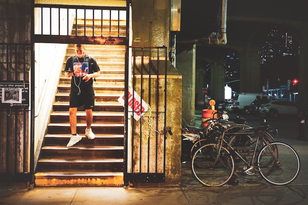 woman in black t-shirt and blue denim shorts standing beside brown wooden door