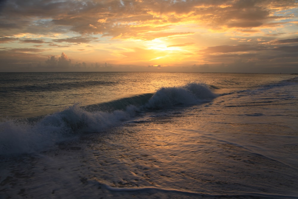 ocean waves crashing on shore during sunset