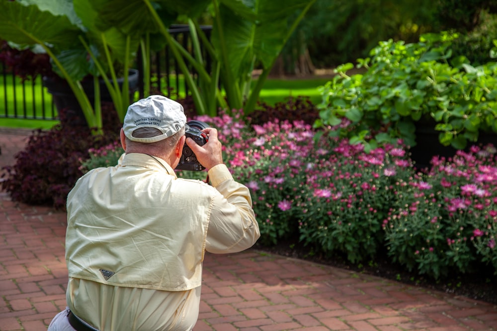 a man taking a picture of a flower garden