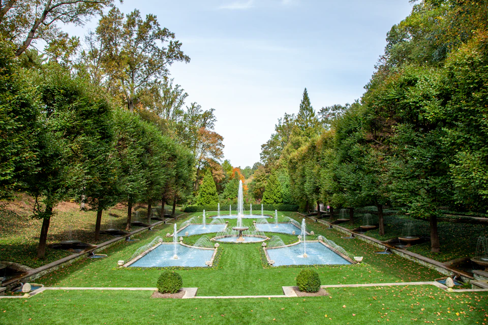 Serene garden scene with large fountain surrounded by multiple pools and stone walls