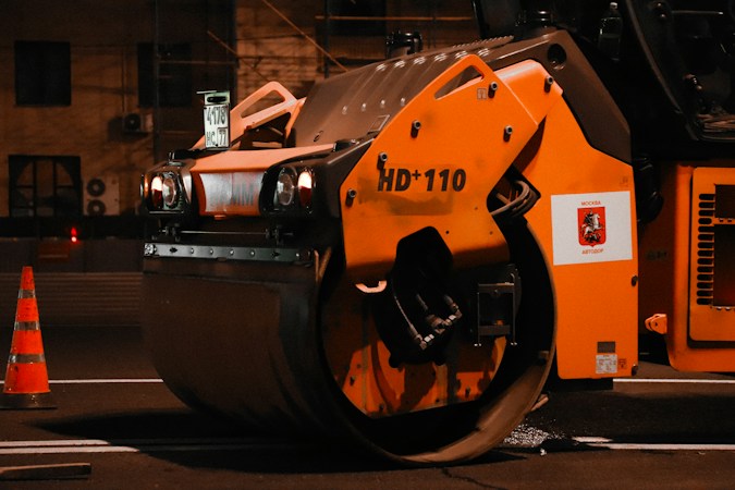 Heavy road construction equipment at night, similar to the milling and paving machines used on I-11/U.S. 95 in Las Vegas