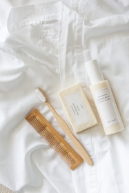A neatly folded stack of neutral-toned linen clothes next to a small bowl of natural skincare products, inviting gentle self-care rituals.