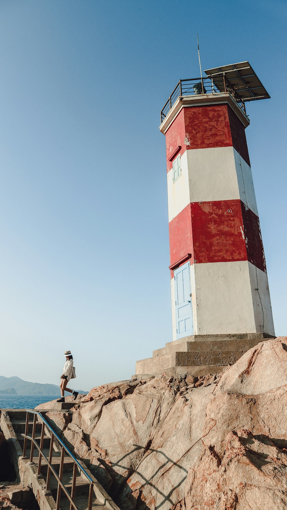 man in gray t-shirt and black pants standing on brown rock near red and white