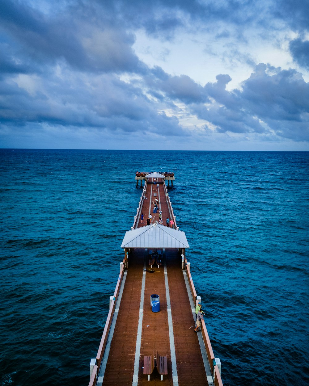 Braunes Holzdock am blauen Meer unter blauem und weißem bewölktem Himmel tagsüber