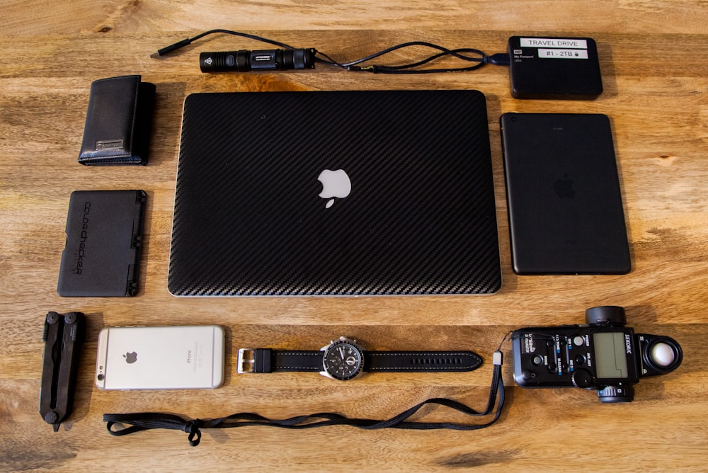 silver macbook beside black and silver round analog watch