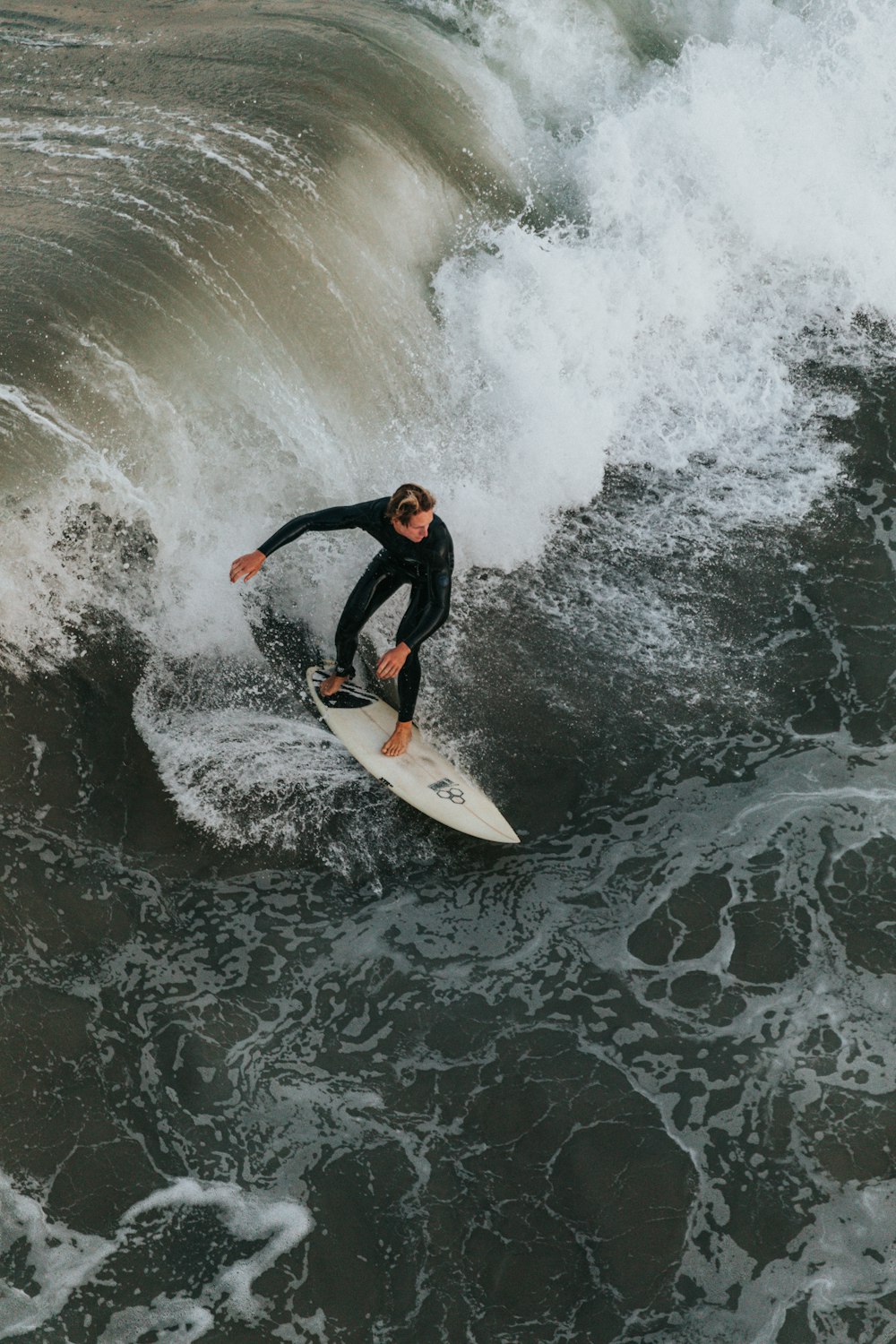 man in black wetsuit surfing on water waves during daytime