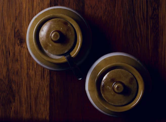 Close-up of elegant ceramic spice jars with silver lids on a dark wooden tray.
