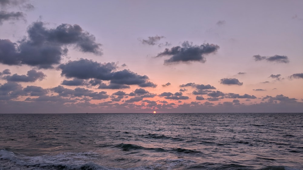 ocean waves under cloudy sky during sunset