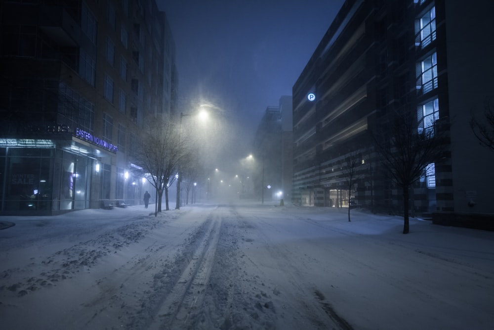 snow covered road between buildings during night time