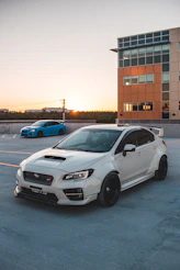 A sleek black car with a custom widebody kit parked on an urban street at sunset.