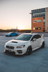A sleek black car with a custom widebody kit parked on an urban street at sunset.