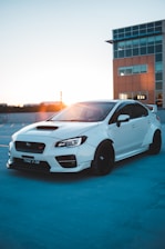 Luxury white sports car parked elegantly against a city skyline at sunset.