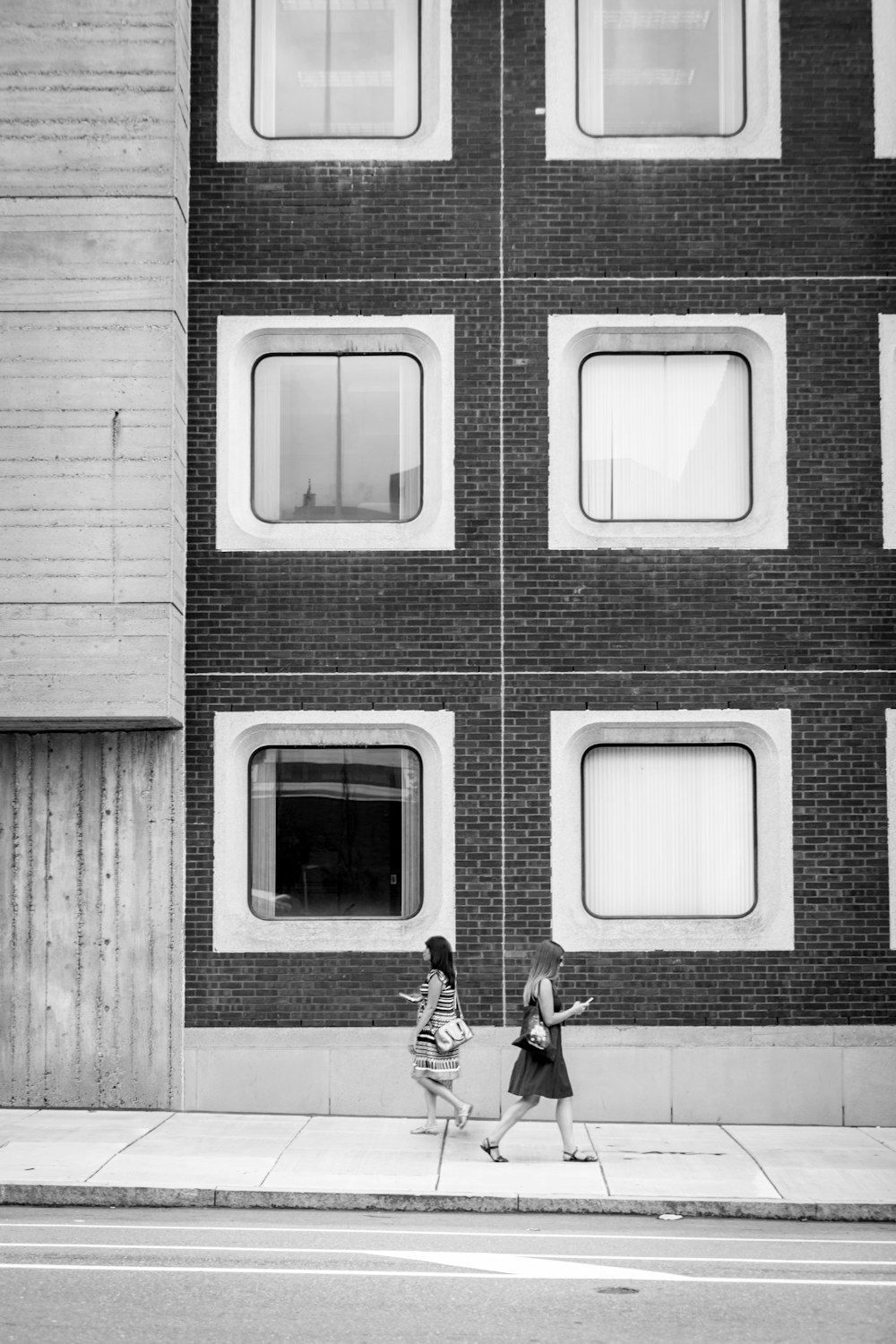 grayscale photo of man in black jacket and pants sitting on window