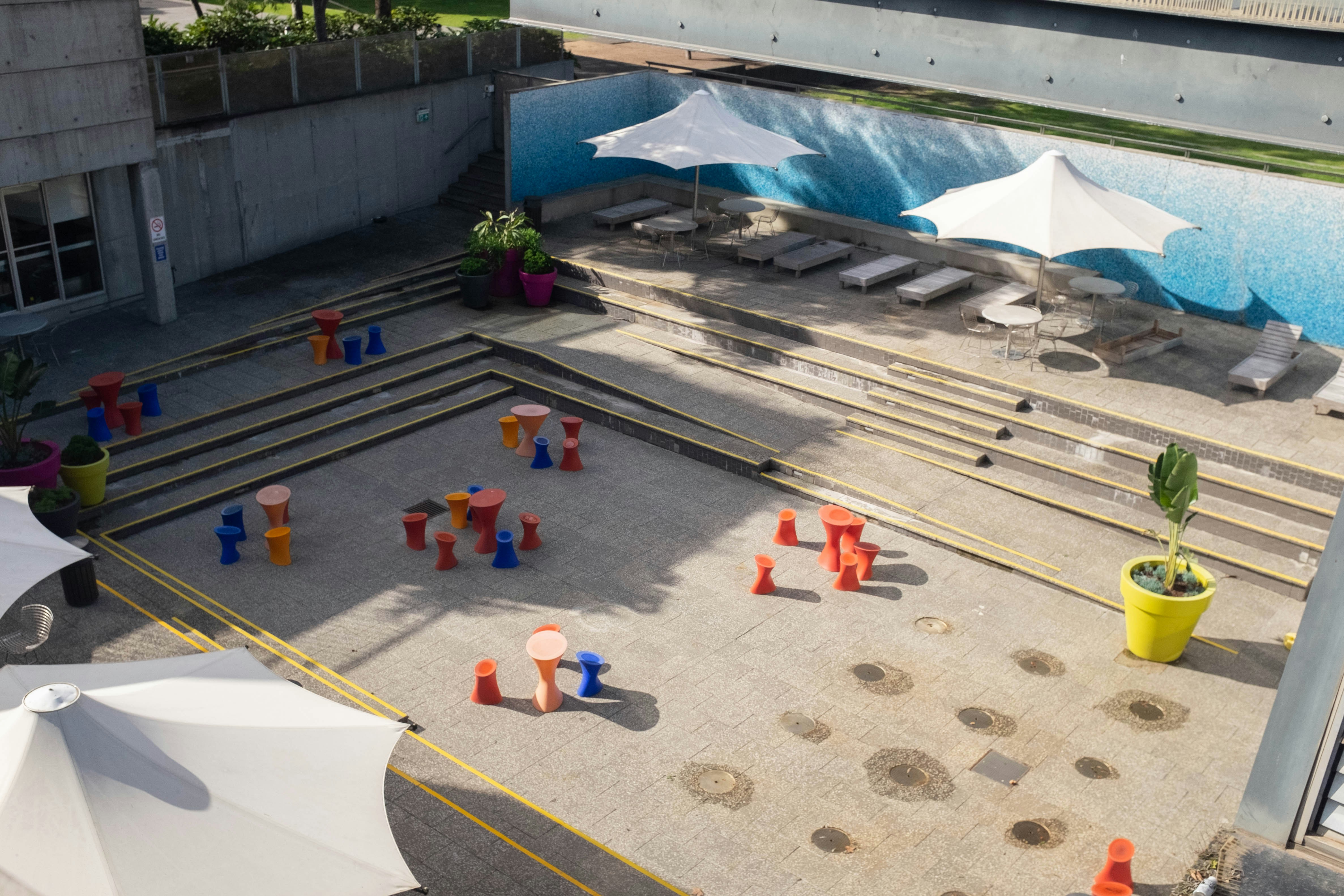 Outdoor area with lounge chairs, umbrellas, and colorful play structures.