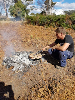 An influencer cooking over a campfire surrounded by nature.