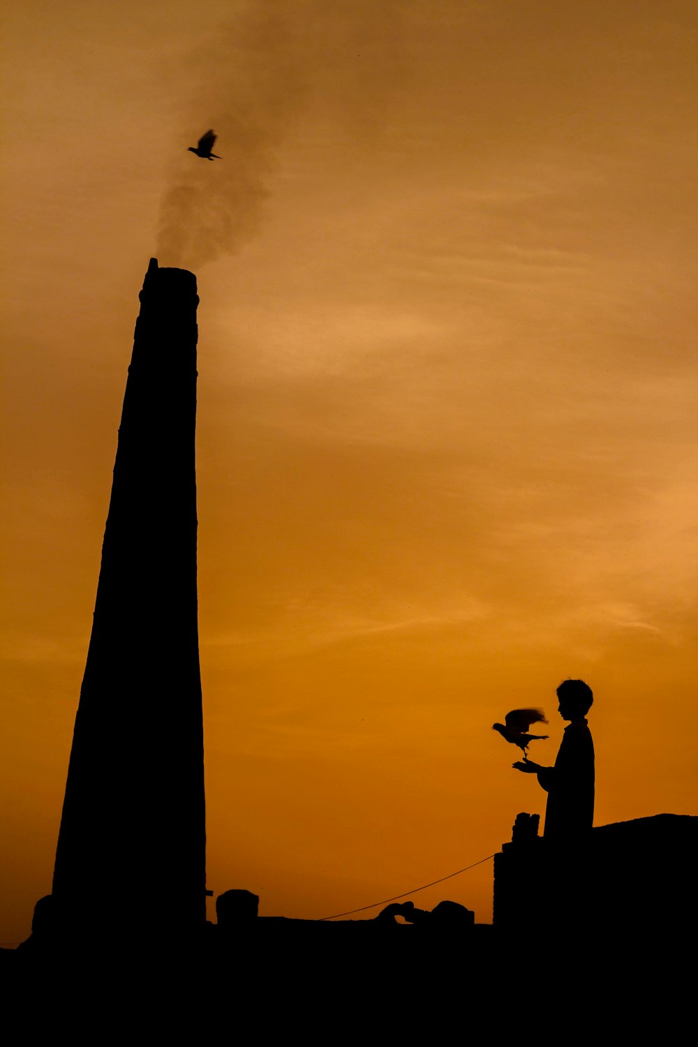 silhouette of man and woman sitting on concrete post under cloudy sky during daytime