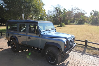 A sturdy blue SUV ready for adventure, parked on a gravel lot with trees in the background.