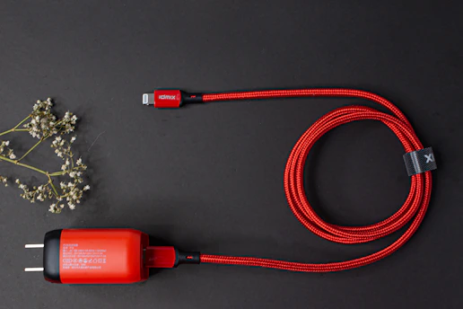 A set of electric blue charging cables neatly coiled on a sleek white surface with subtle glassmorphism effects.