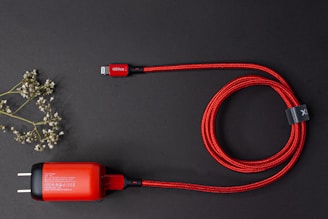 Close-up of sleek charging cables coiled beside a smartphone on a clean white surface.