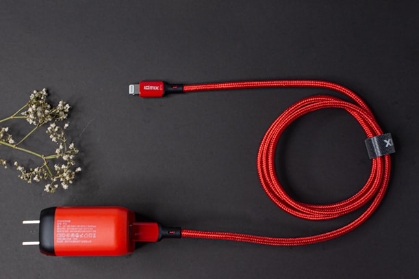 Close-up of sleek charging cables coiled beside a smartphone on a clean white surface.