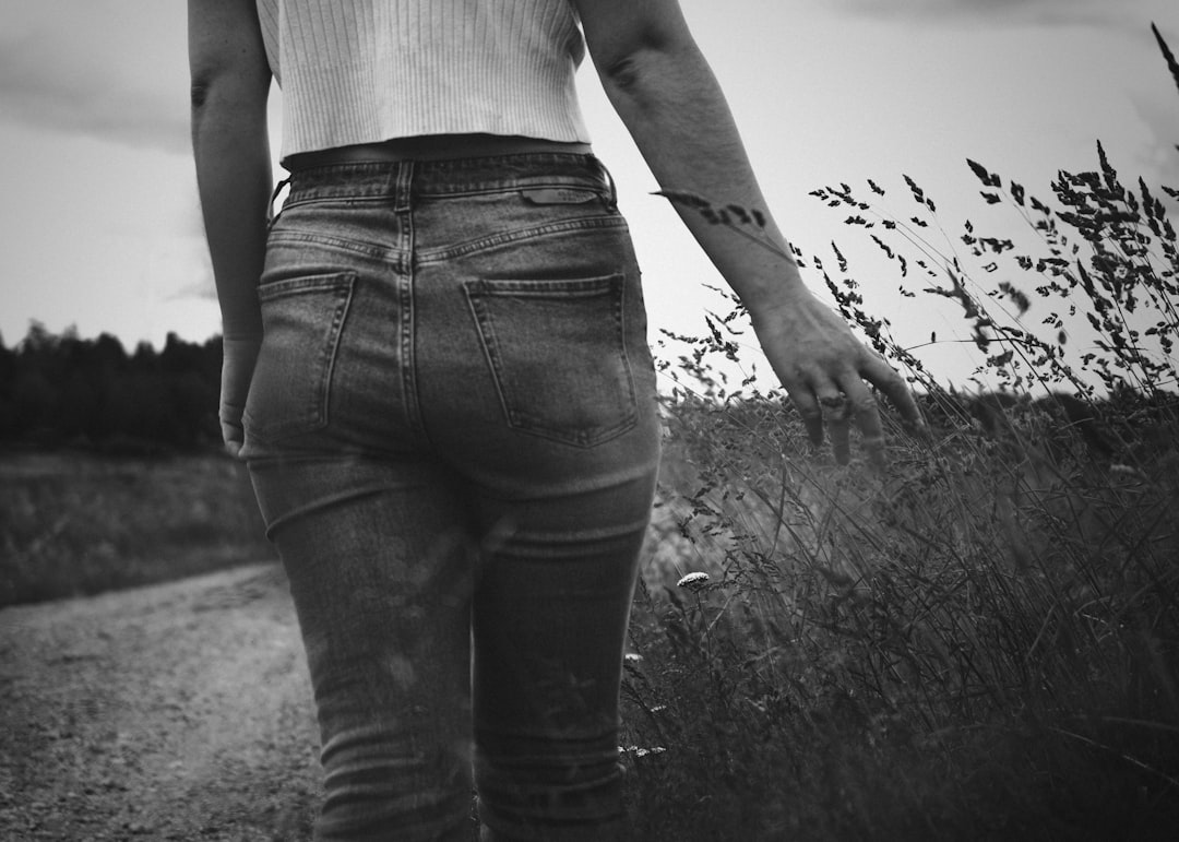 grayscale photo of woman in white tank top and black denim jeans