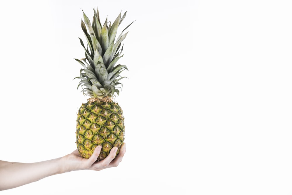 frutta dell'ananas sulla mano delle persone