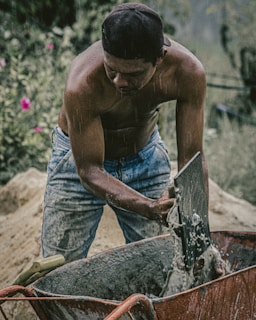 topless man in blue denim jeans holding brown wooden stick