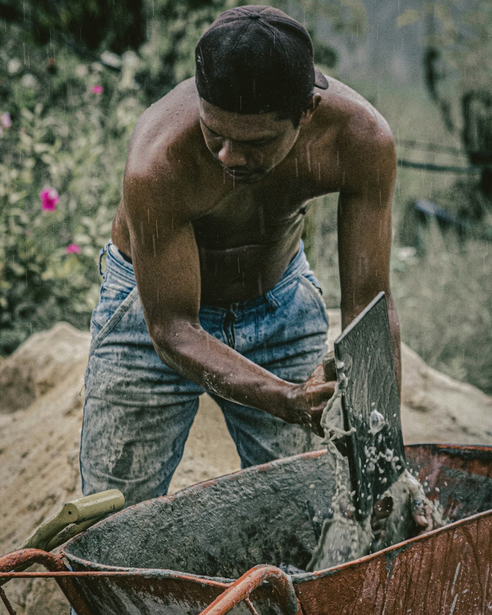 topless man in blue denim jeans holding brown wooden stick