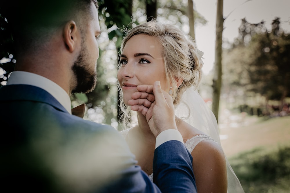 homme en costume bleu embrassant femme en robe de mariée blanche