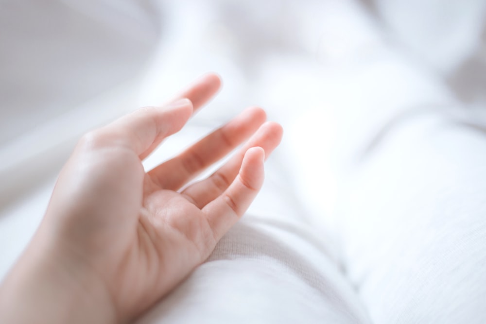 persons hand on white textile