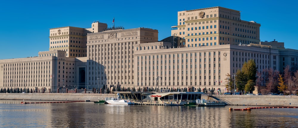 white and blue boat on water near brown concrete building during daytime