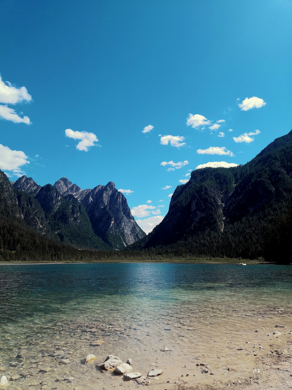 green mountains beside body of water under blue sky during daytime