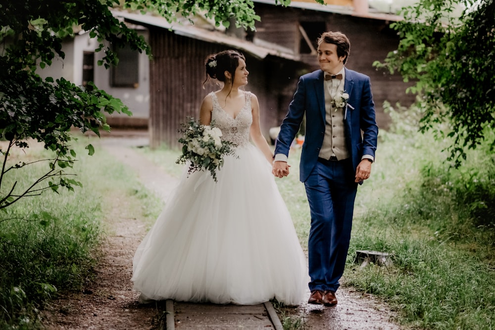 Frau im weißen Hochzeitskleid neben Mann im blauen Anzug