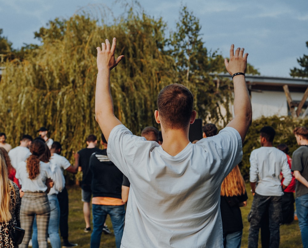 man in white long sleeve shirt raising his hands