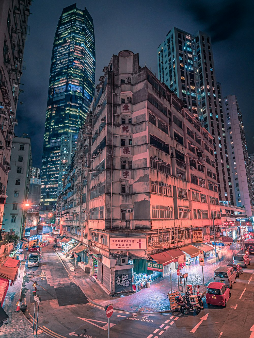 cars on road between high rise buildings during night time