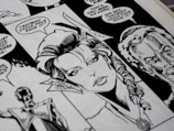 A close-up view of a black and white comic book page featuring detailed illustrations of characters with speech bubbles. The main character has a braided hairstyle, and the speech text includes a dialogue questioning who could have done something.
