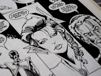 A close-up view of a black and white comic book page featuring detailed illustrations of characters with speech bubbles. The main character has a braided hairstyle, and the speech text includes a dialogue questioning who could have done something.