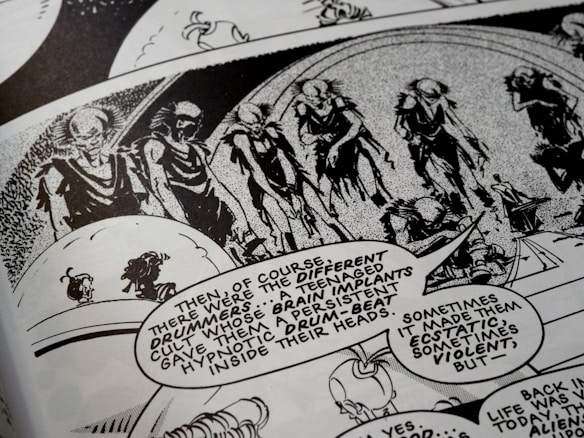 A black-and-white comic book page features a series of humanoid figures with skeletal appearances marching in a procession. The scene is accompanied by speech bubbles with dialogue describing a cult and brain implants that produce a drumbeat, impacting emotions. The artwork is detailed with an abstract background, enhancing the surreal, eerie atmosphere.