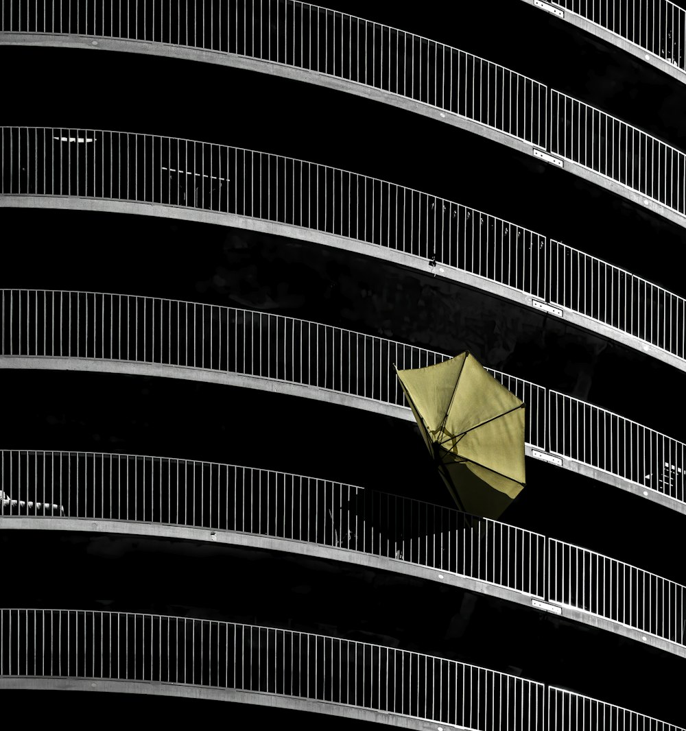 yellow umbrella on black and white spiral staircase