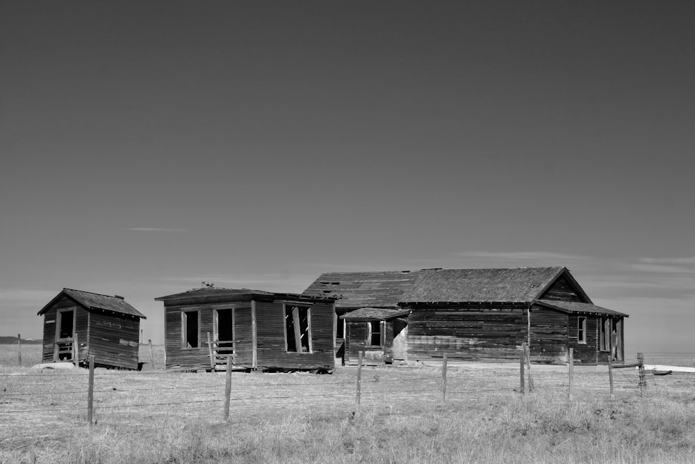 grayscale photo of wooden house on grass field