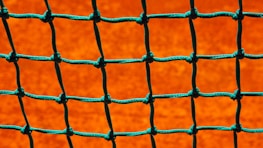 Close-up of high-quality safety net material stretched tightly on a sports field.