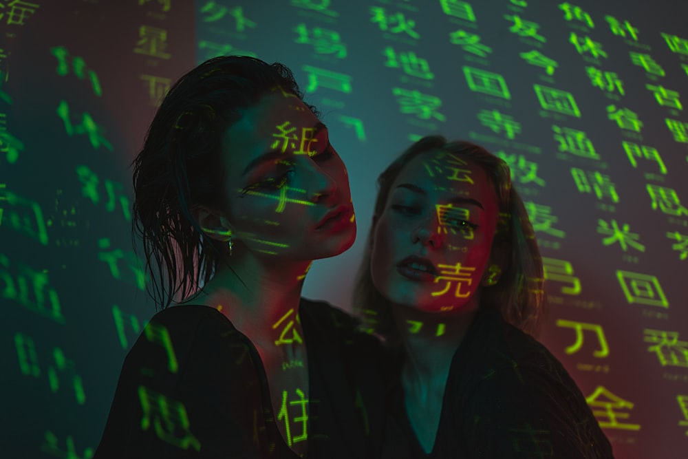 woman in black jacket standing beside blue and green neon light signage