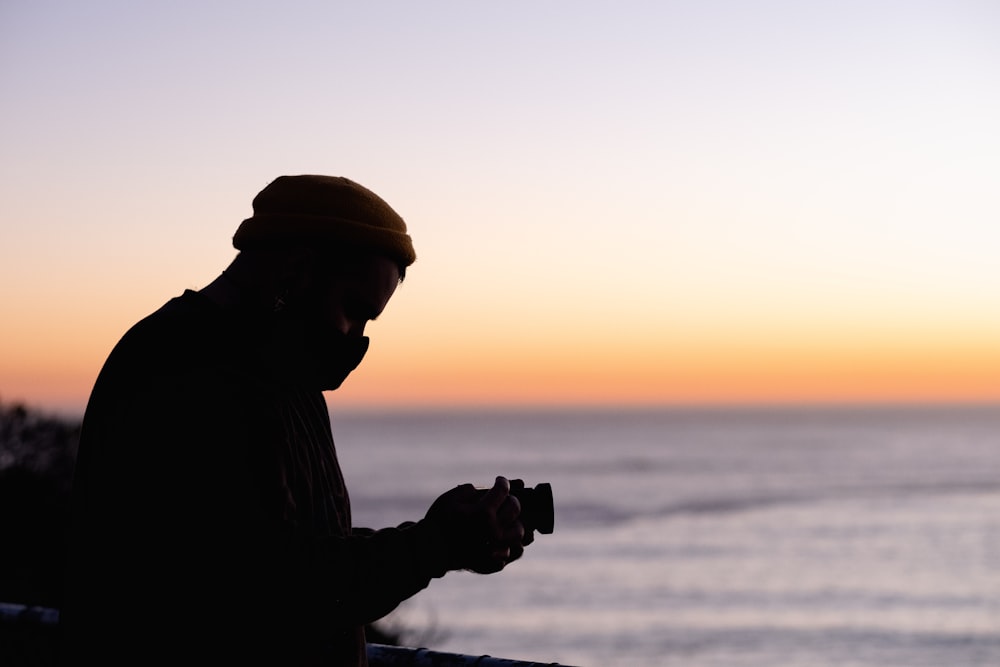 silhouette of man holding camera during sunset