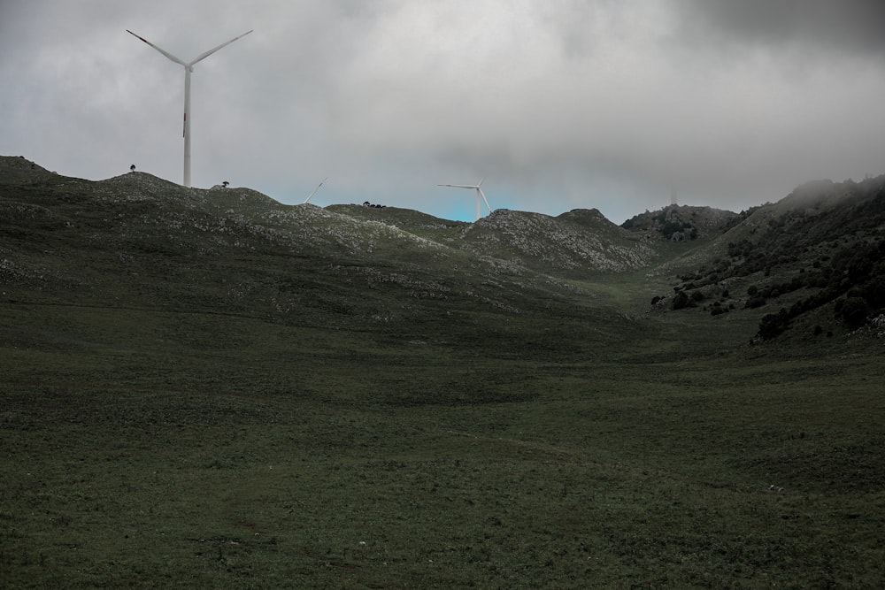 green grass field with wind turbines under white clouds during daytime