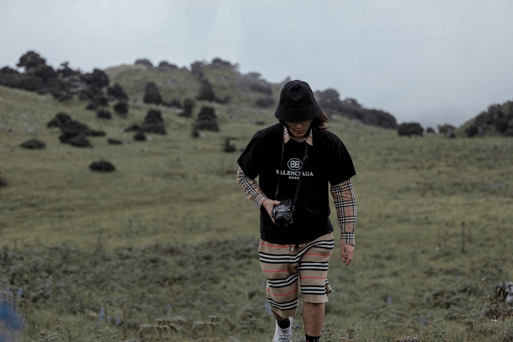 man in black t-shirt and brown shorts standing on green grass field during daytime