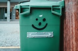 green trash bin on sidewalk