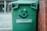 A satisfied customer giving a thumbs up in front of a recycling bin.